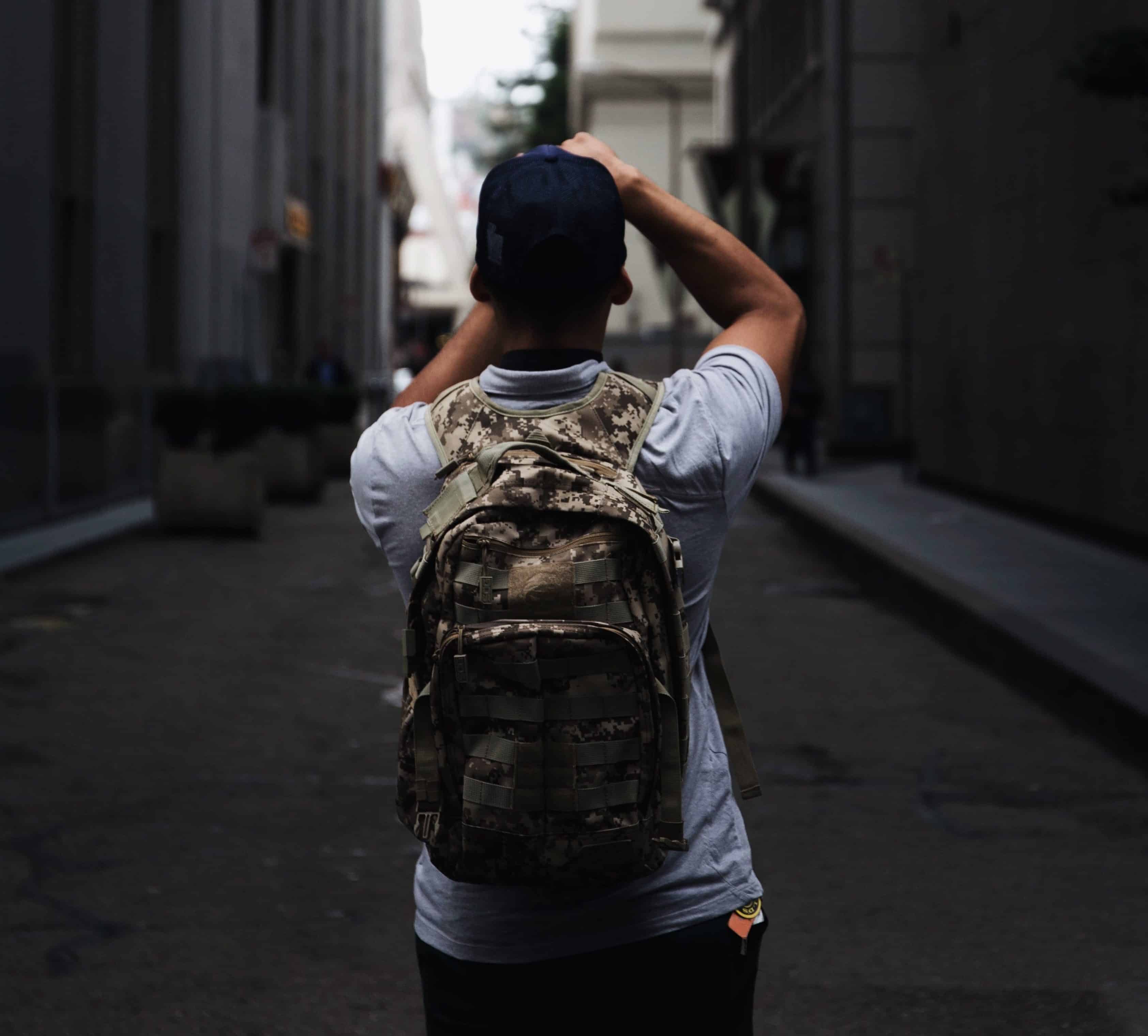 Man with tactical backpack on in city taking photos