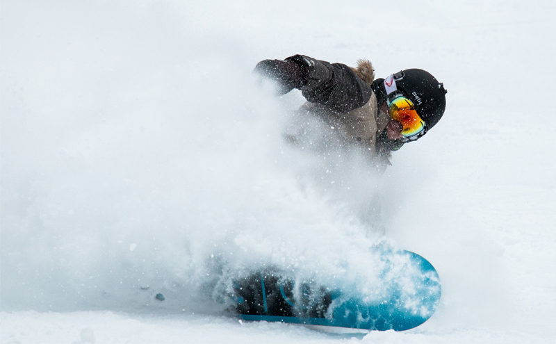 Snowboarder sliding in powdery snow.