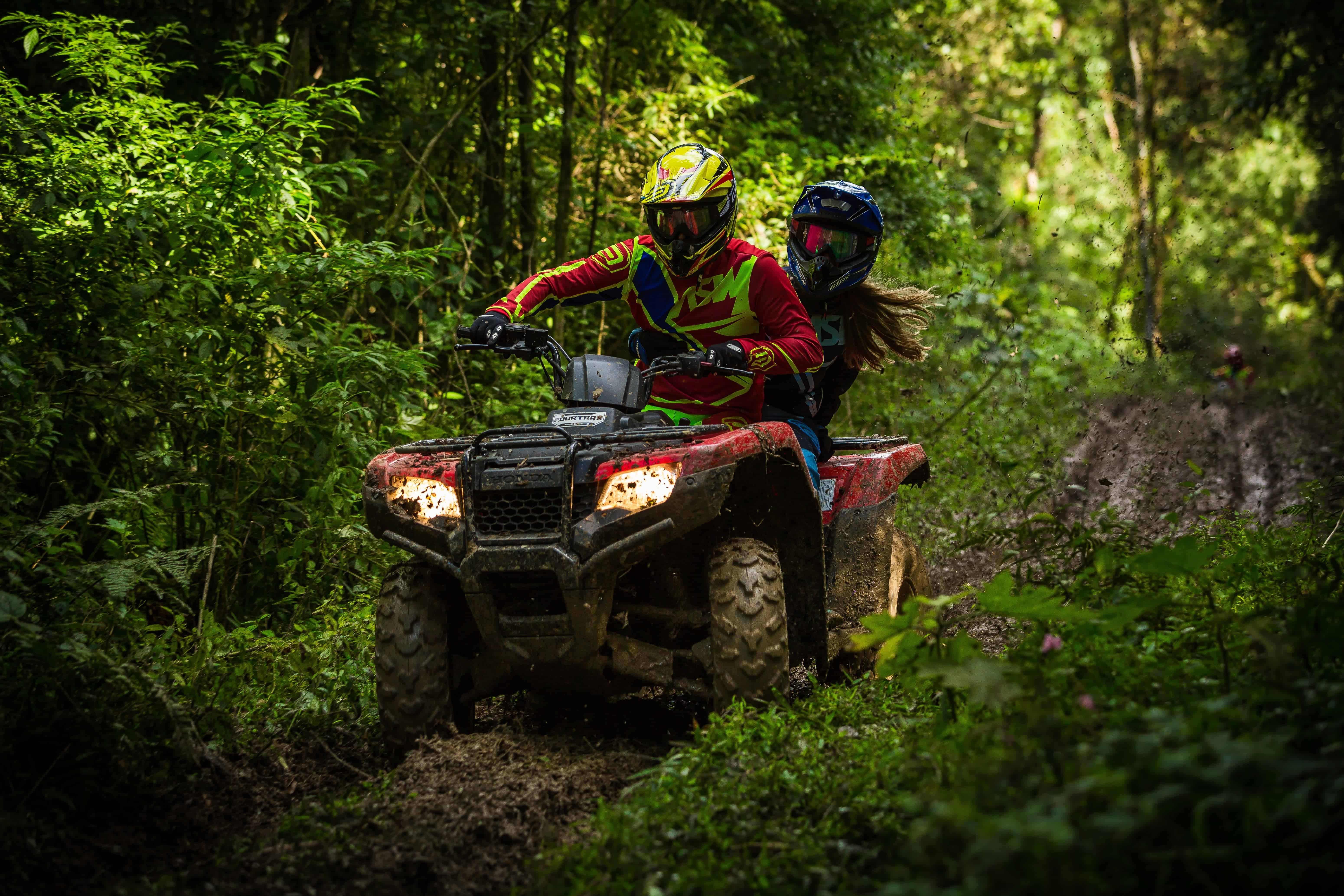 Man and woman riding on an ATV in the woods