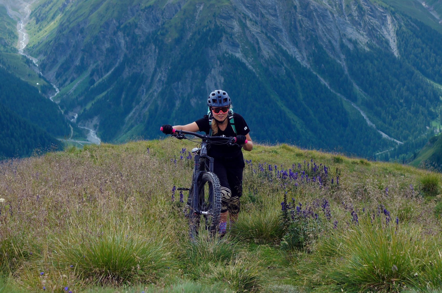 Woman pushing mountain bike uphill.