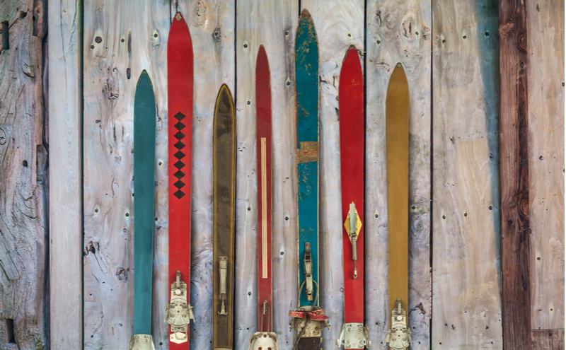 Collection of vintage wooden weathered ski's in front of an old barn.