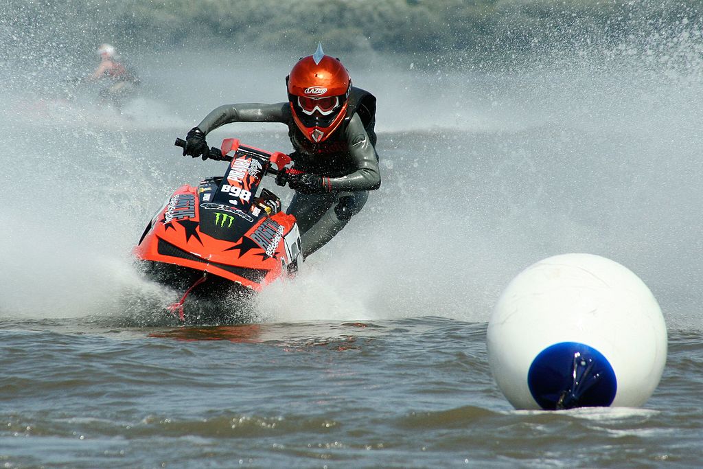 Jet ski rider with helmet going around an obstacle.
