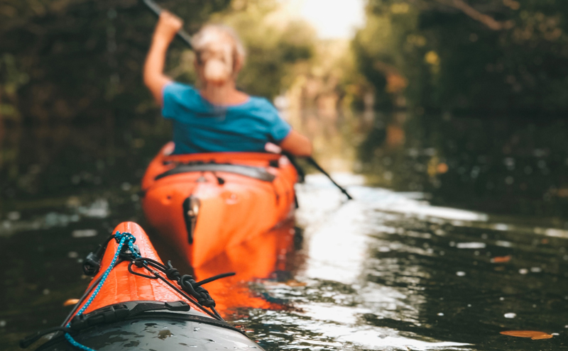 Couple kayaking across a narrow river.