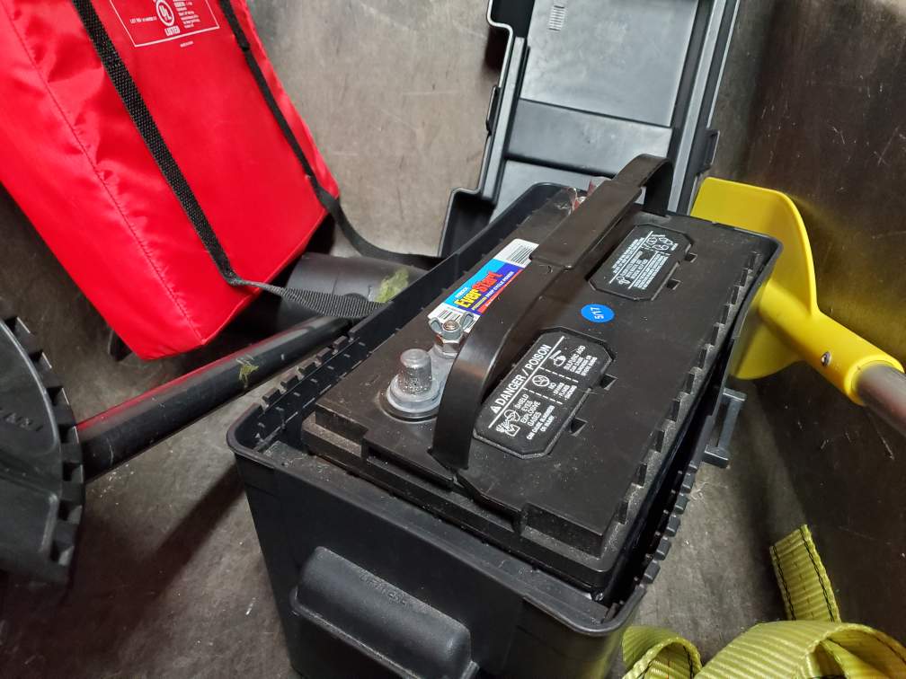 Jon boat battery inside battery box with other boating gear.